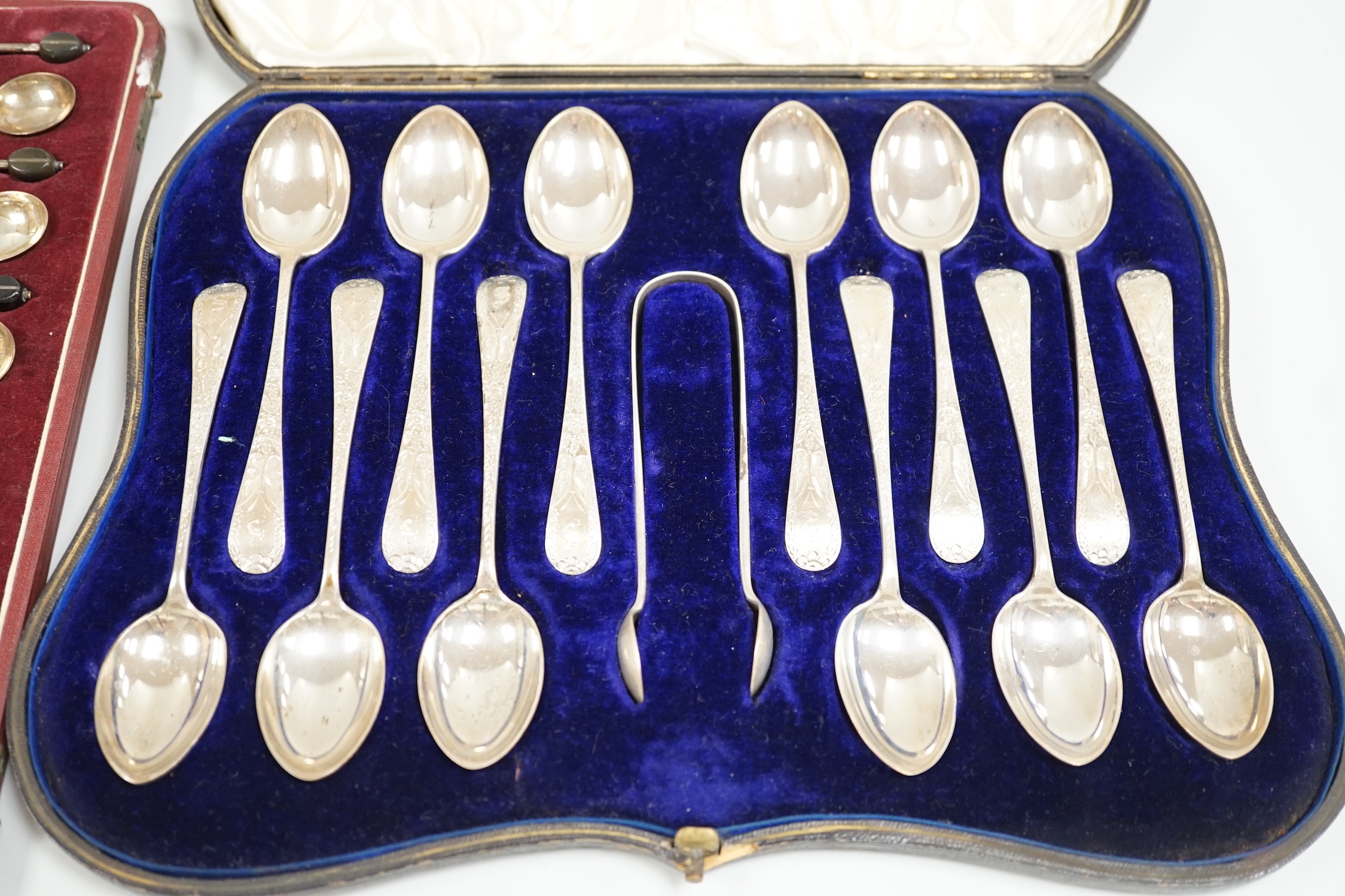 A cased set of twelve Edwardian Scottish silver teaspoons with sugar tongs, Lawson & Co, Glasgow, 1904 and a cased set of twelve sterling bean end coffee spoons, by Alexander Clark Co. Shanghai.